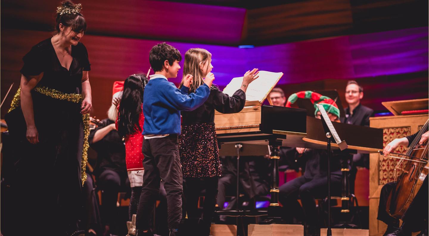 Children on stage, surrounded by musicians