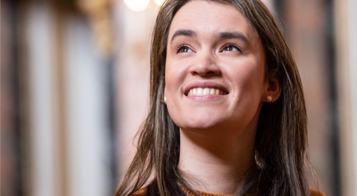 a woman with long brown hair smiles beyond the camera, looking upwards