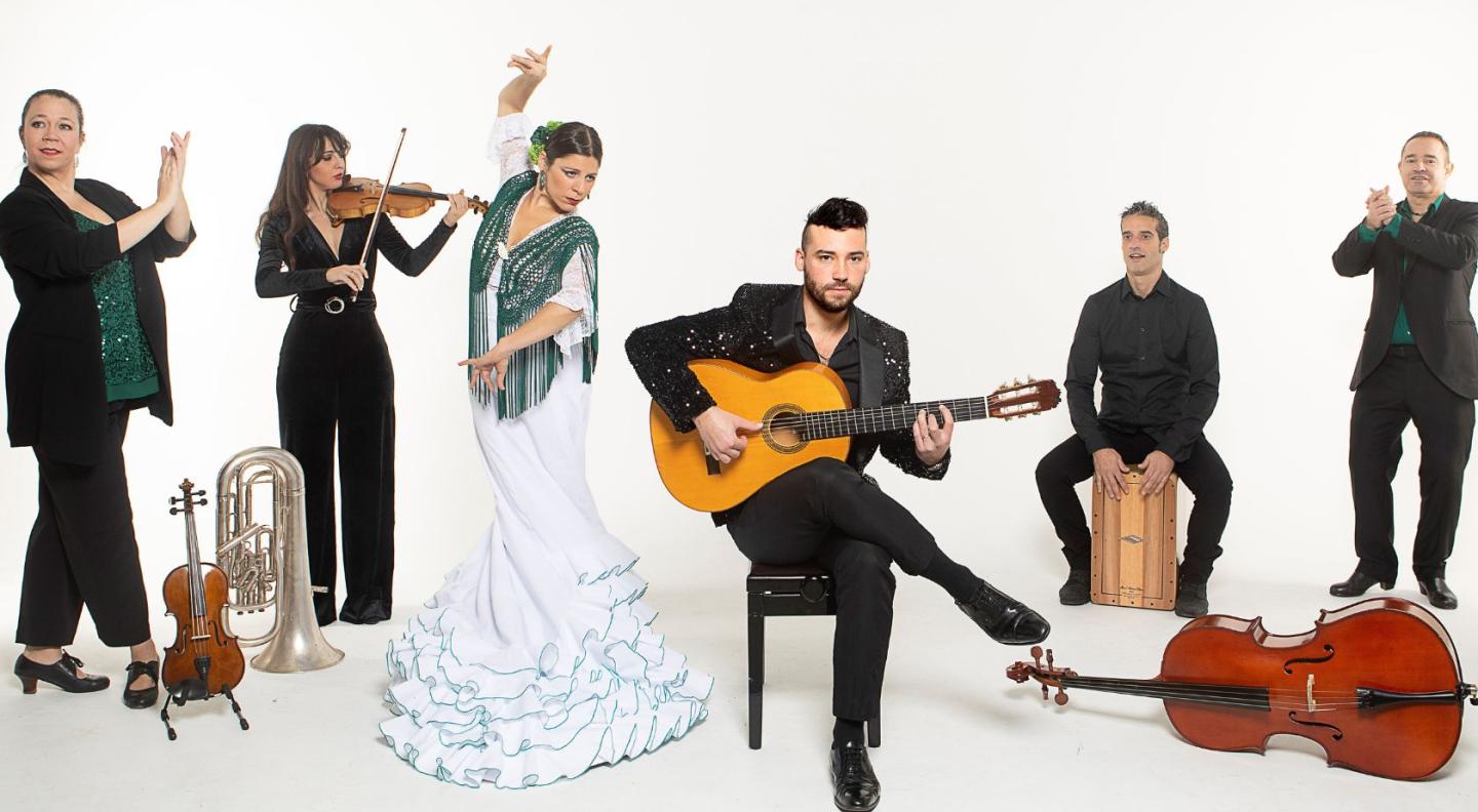 musicians and dancers in traditional costume stand posed against a white background