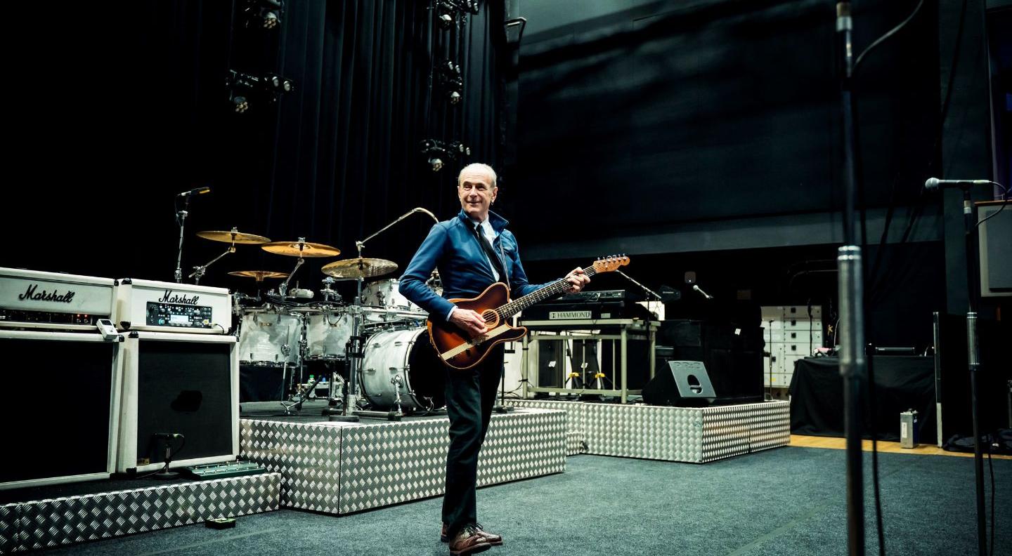 An image of Francis on stage with a guitar