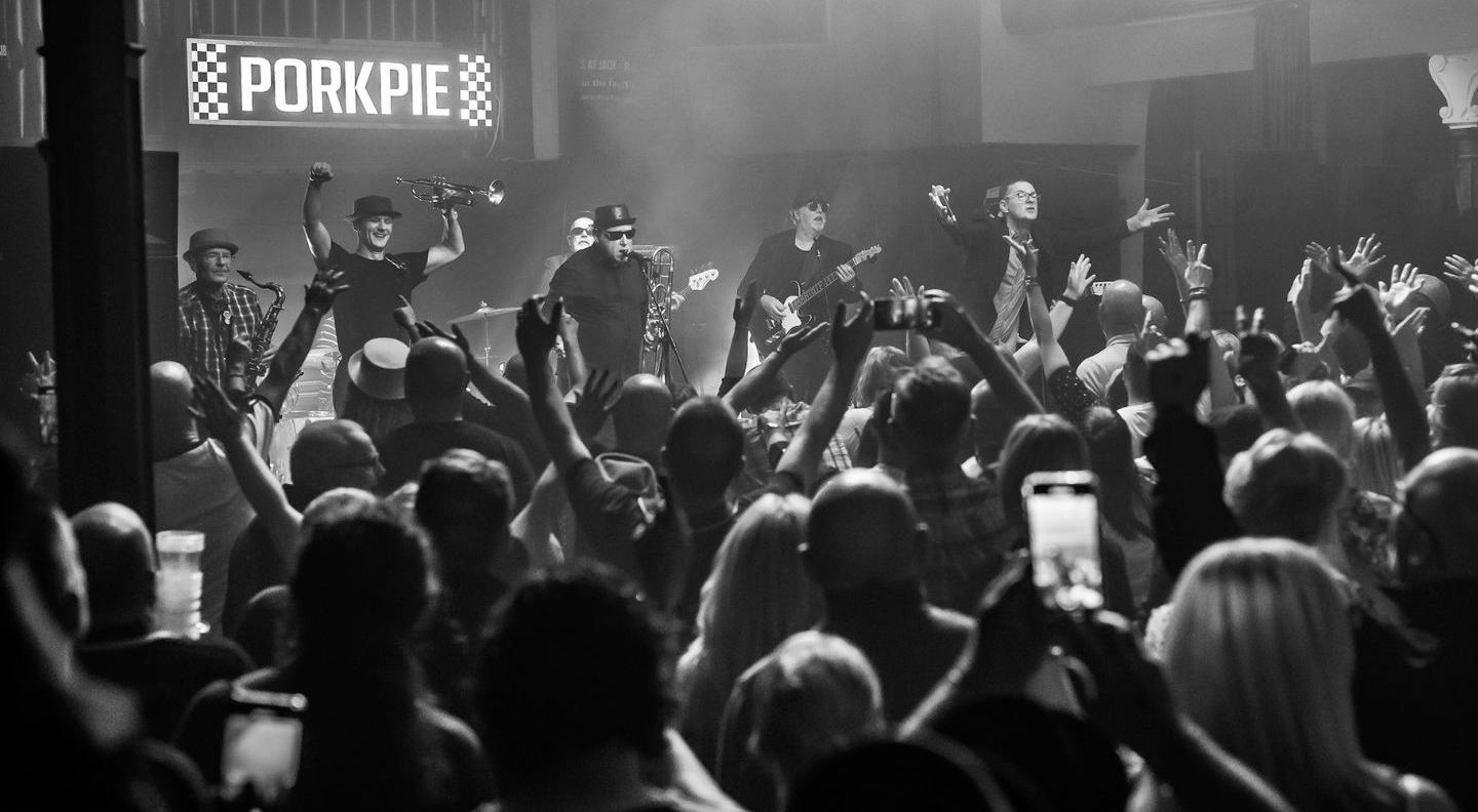 a black and white image of the band on stage in front of  a cheering crowd