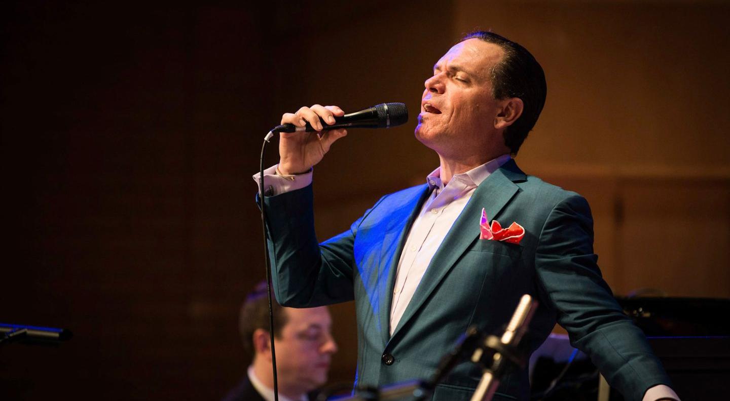 an image of a jazz singer performing on stage, wearing a green tuxedo