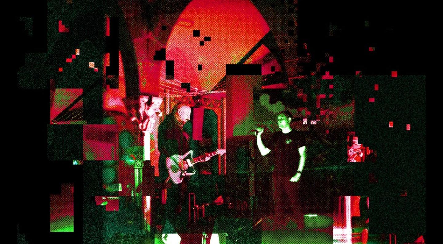 a dark, pixelated image of the band on stage